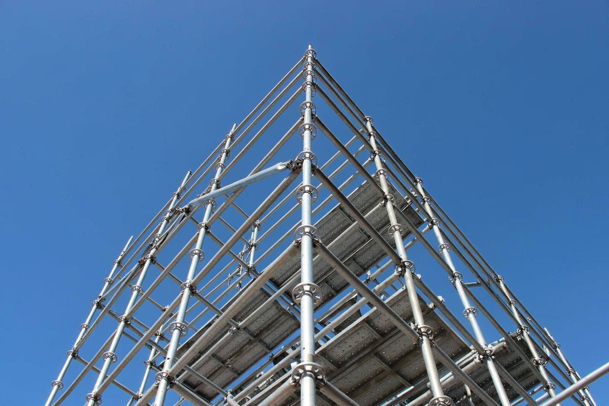 Ringlock scaffolding tower photographed from below against a blue sky, showing standards, ledgers and diagonal braces